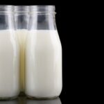 Three bottles of milk isolated in black background
